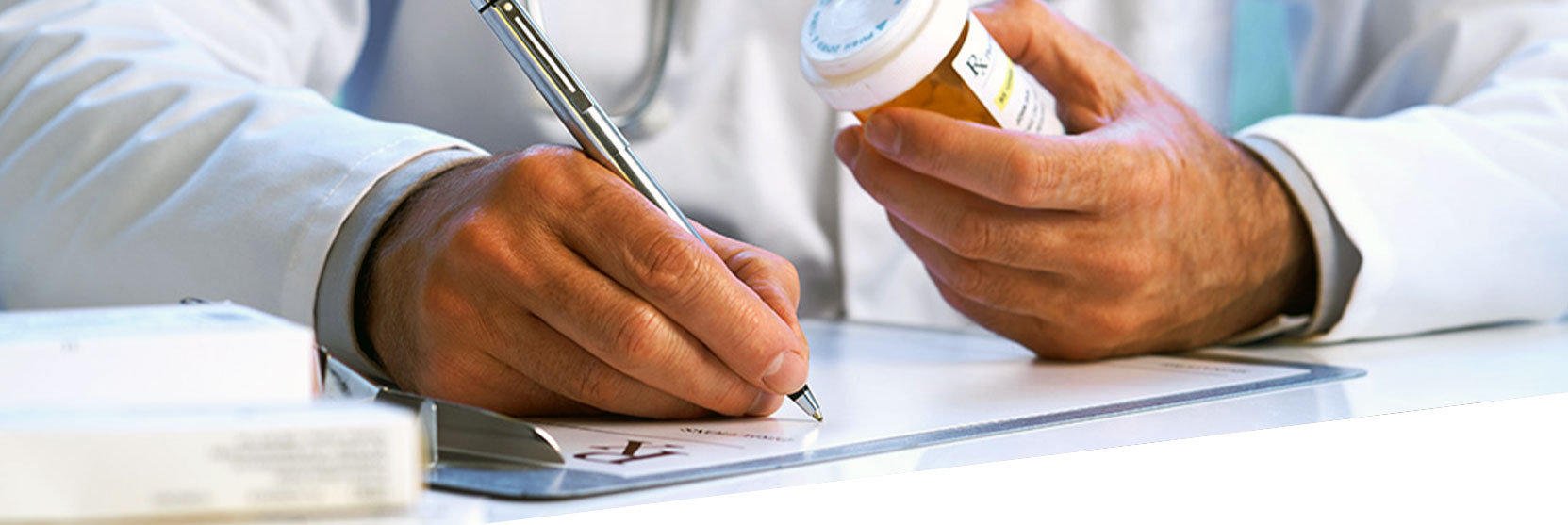 A doctor writing a prescription while holding a pill bottle